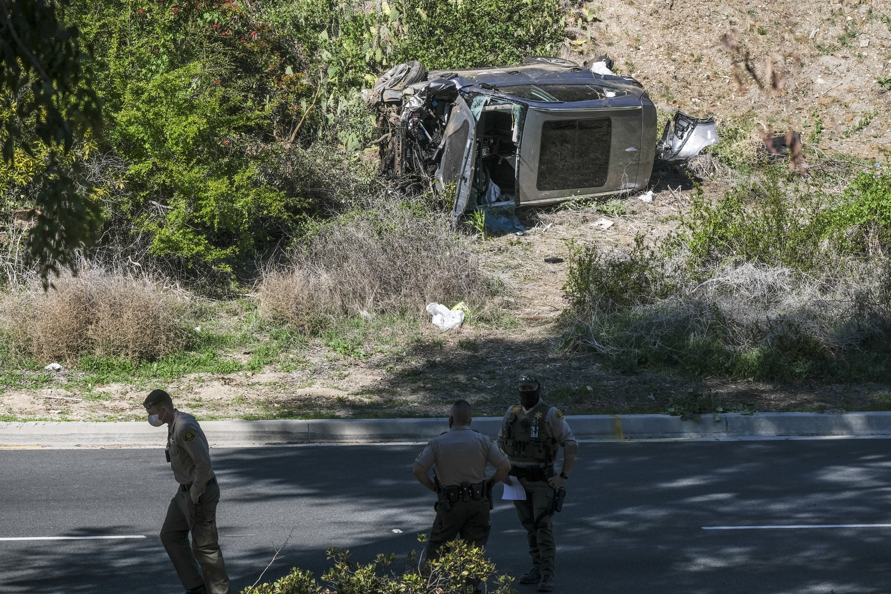 In this Feb. 23, 2021, file photo a vehicle rests on its side after a rollover accident involving golfer Tiger Woods along a road in the Rancho Palos Verdes suburb of Los Angeles. (AP Photo/Ringo H.W. Chiu, File)