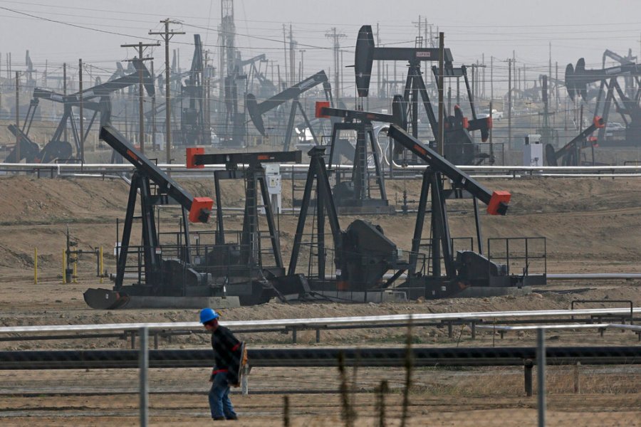 In this Jan. 16, 2015, file photo, a person walks past pump jacks operating at the Kern River Oil Field in Bakersfield, Calif. (AP Photo/Jae C. Hong, File)