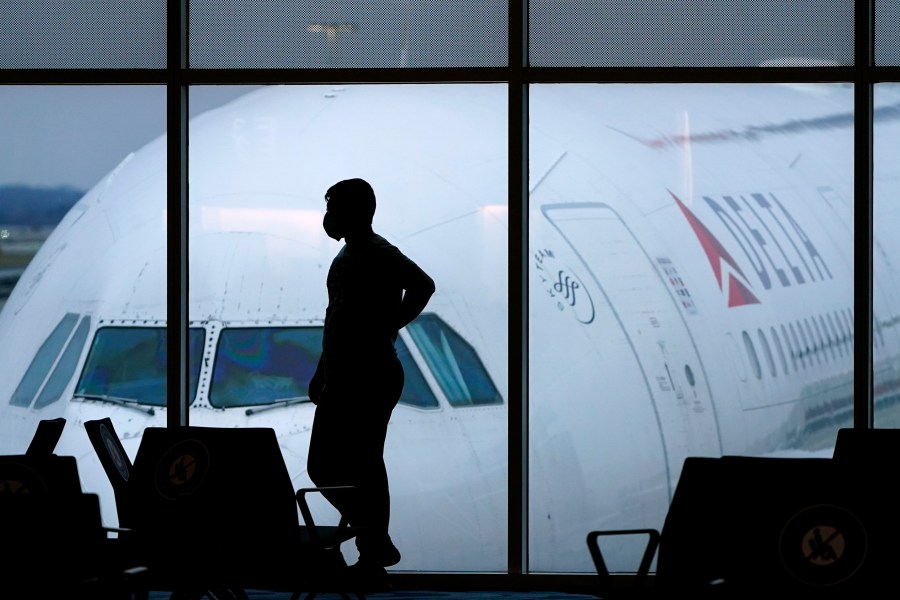 In this Feb. 18, 2021 file photo, a passenger wears a face mask to help prevent against the spread of the coronavirus as he waits for a Delta Airlines flight at Hartsfield-Jackson International Airport in Atlanta. (AP Photo/Charlie Riedel, File)