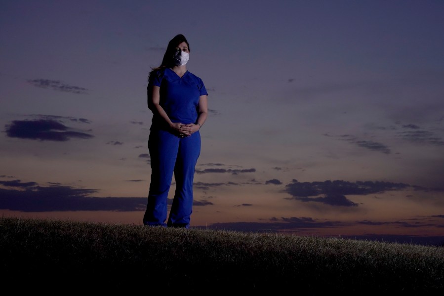 Emergency room nurse L'Erin Ogle stands at dawn before starting her 12-hour shift at a nearby hospital Tuesday, March 9, 2021, in Overland Park, Kan. (AP Photo/Charlie Riedel)