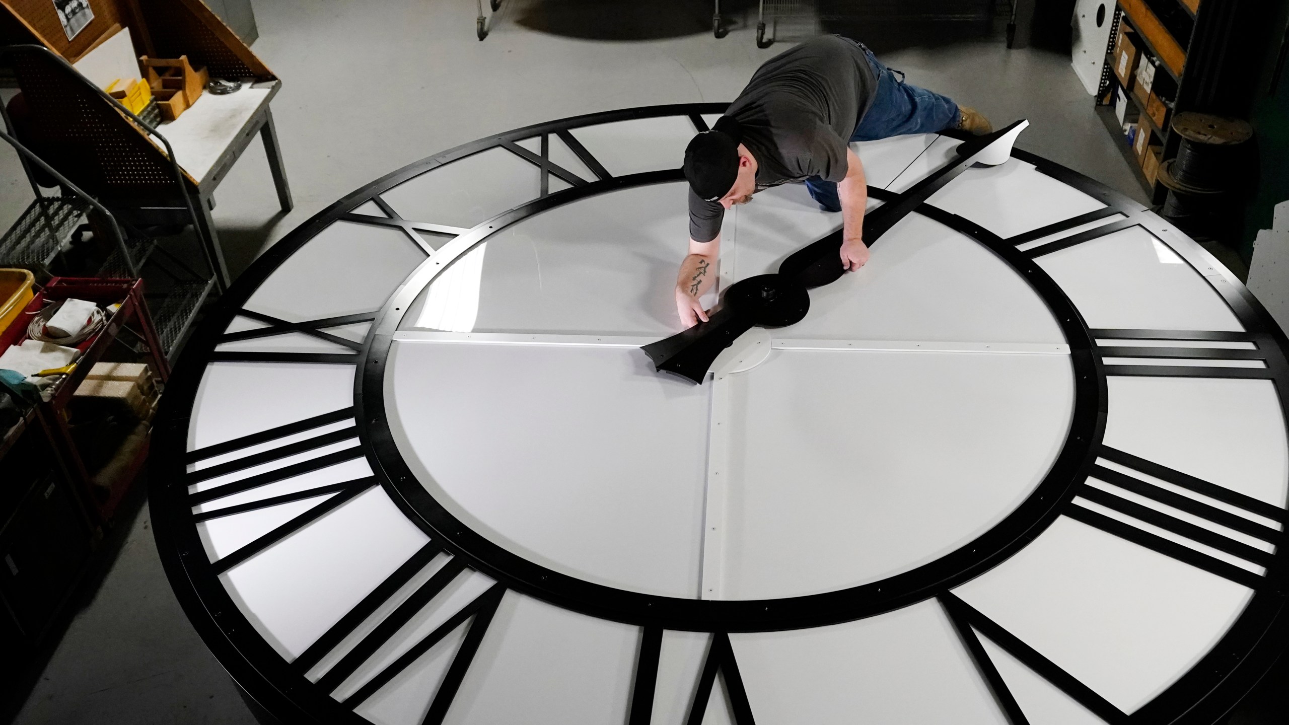 Electric Time technician Dan LaMoore puts a clock hand onto a 1000-lb., 12-foot diameter clock constructed for a resort in Vietnam, Tuesday, March 9, 2021, in Medfield, Mass. Daylight saving time begins at 2 a.m. local time Sunday, March 14, 2021, when clocks are set ahead one hour. (AP Photo/Elise Amendola)