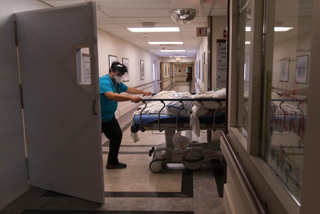 In this Friday, Feb. 19, 2021, file photo, medical transporter Adrian Parrilla moves a patient into a COVID-19 unit at Mission Hospital in Mission Viejo, California. (AP Photo/Jae C. Hong, File)