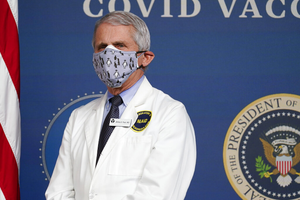 In this Feb. 25, 2021, Dr. Anthony Fauci, director of the National Institute of Allergy and Infectious Diseases, listens as President Joe Biden speaks during an event to commemorate the 50 millionth COVID-19 shot in Washington. Fauci said Sunday, March 14, he wishes former President Donald Trump would use his popularity among Republicans to persuade his followers to get the COVID-19 vaccine. (AP Photo/Evan Vucci, File)