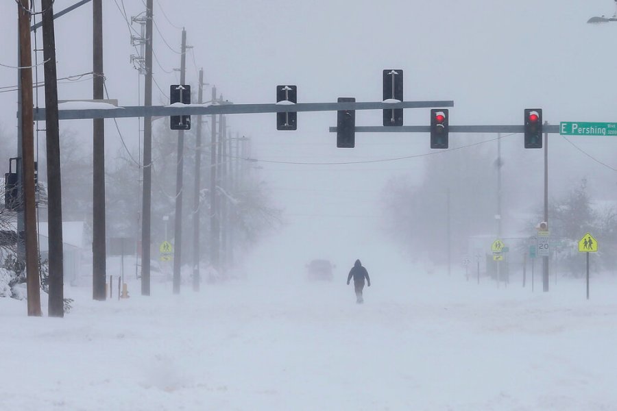 A person trudges across Ridge Road in east Cheyenne, Wyo, Sunday, March 14, 2021. (Michael Cummo/Wyoming Tribune Eagle via AP)