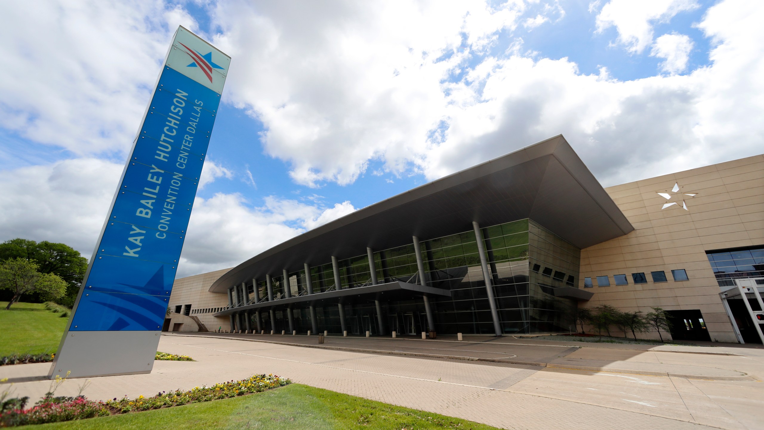 In this March 31, 2020 file photo, a leaning sign sits in front of the Kay Bailey Hutchison Convention Center in downtown Dallas. The U.S. government plans to use the convention center to hold up to 3,000 immigrant teenagers as sharply higher numbers of border crossings have severely strained the current capacity to hold youths, according to a memo obtained by The Associated Press. Center will be used for up to 90 days beginning as early as this week, according to written notification sent to members of the Dallas City Council on Monday, March 15, 2021. (AP Photo/Tony Gutierrez File)