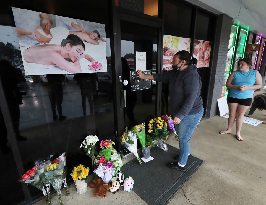 In this March 17, 2021, file photo, Jessica Lang pauses and places her hand on the door in a moment of grief after dropping off flowers with her daughter Summer at Youngs Asian Massage parlor where four people were killed in Acworth, Ga. (Curtis Compton/Atlanta Journal-Constitution via AP, File)