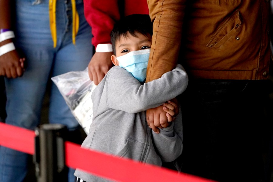 A migrant child holds onto a woman's arm as they wait to be processed by a humanitarian group after being released from U.S. Customs and Border Protection custody at a bus station, Wednesday, March 17, 2021, in Brownsville, Texas. (AP Photo/Julio Cortez)