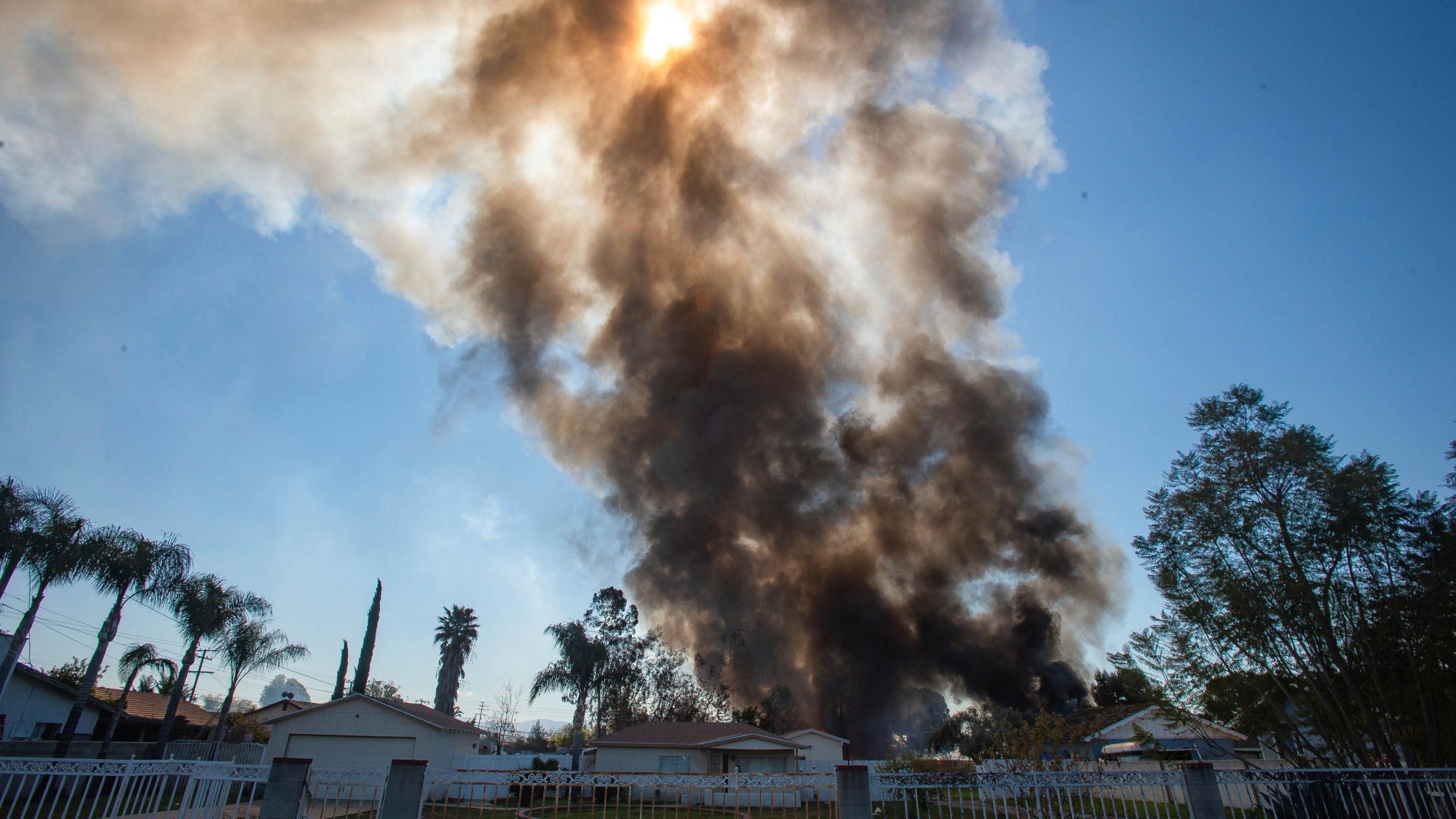 Smoke rises in the background after a fireworks stash exploded in Ontario on March 16, 2021. (Watchara Phomicinda / The Orange County Register via Associated Press)