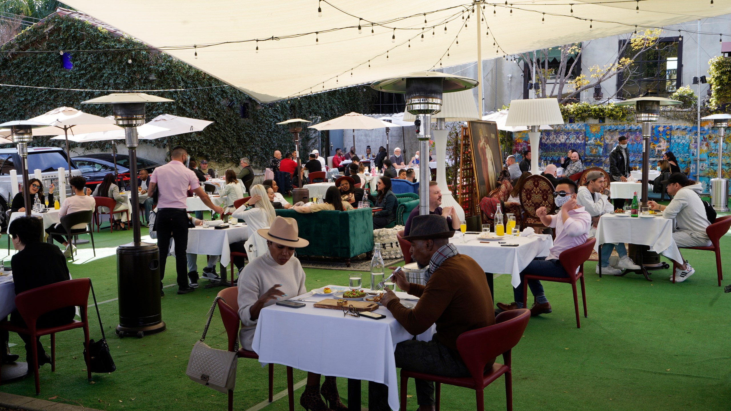 In this Feb. 14, 2021, file photo, people dine under a tent outside a restaurant in West Hollywood, Calif. The California Legislature has delayed a bill that would give a tax break for businesses because of a provision in the latest federal coronavirus relief bill that bans states form using federal stimulus dollars to pay for tax cuts. Gov. Gavin Newsom's administration is worried the U.S. Treasury Department might view the bill as a tax cut and require the state to pay back some of the stimulus money it is owed. (AP Photo/Damian Dovarganes, File)