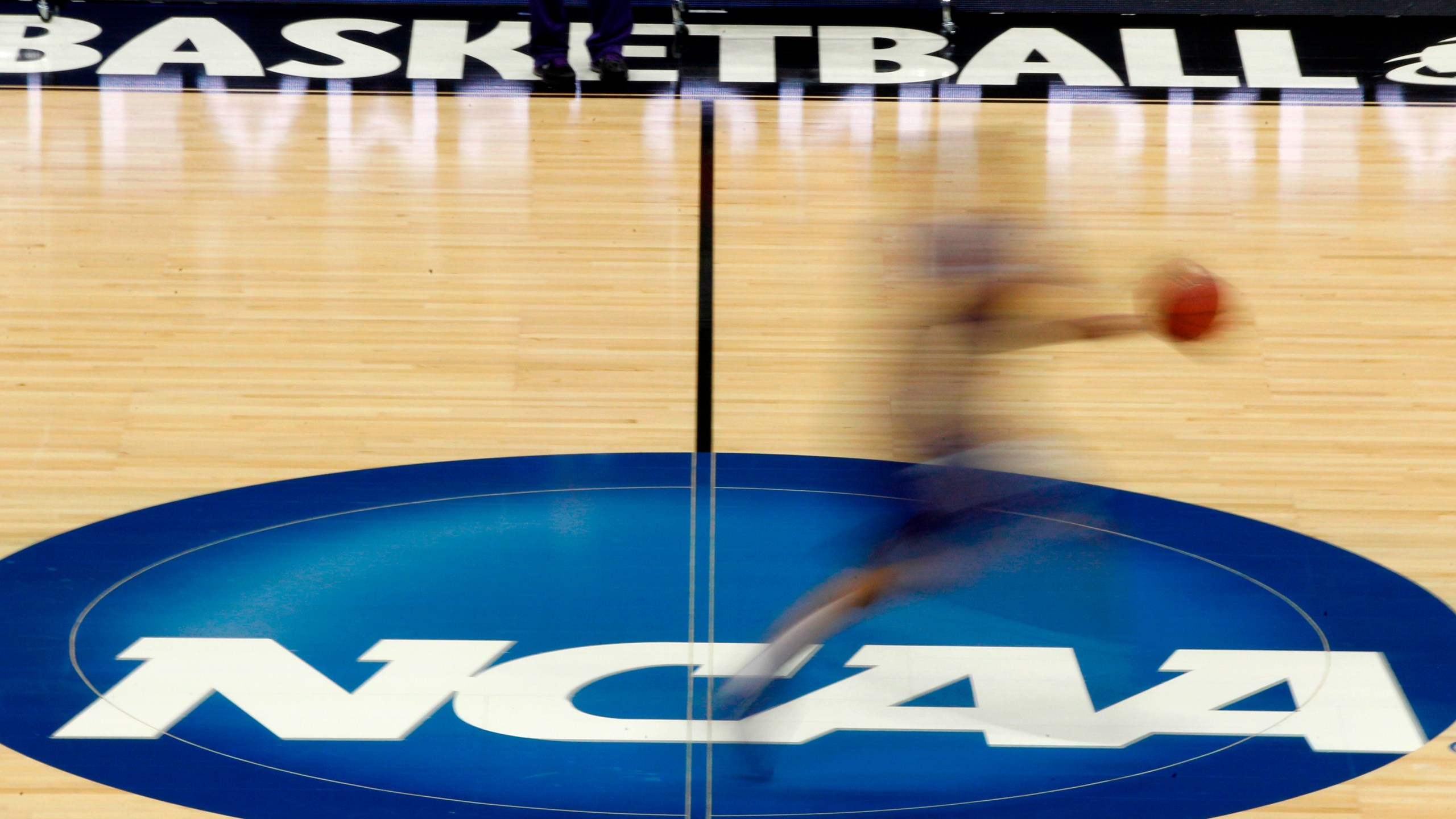 In this March 14, 2012, file photo, a player runs across the NCAA logo during practice in Pittsburgh before an NCAA tournament college basketball game. (AP Photo/Keith Srakocic, File)