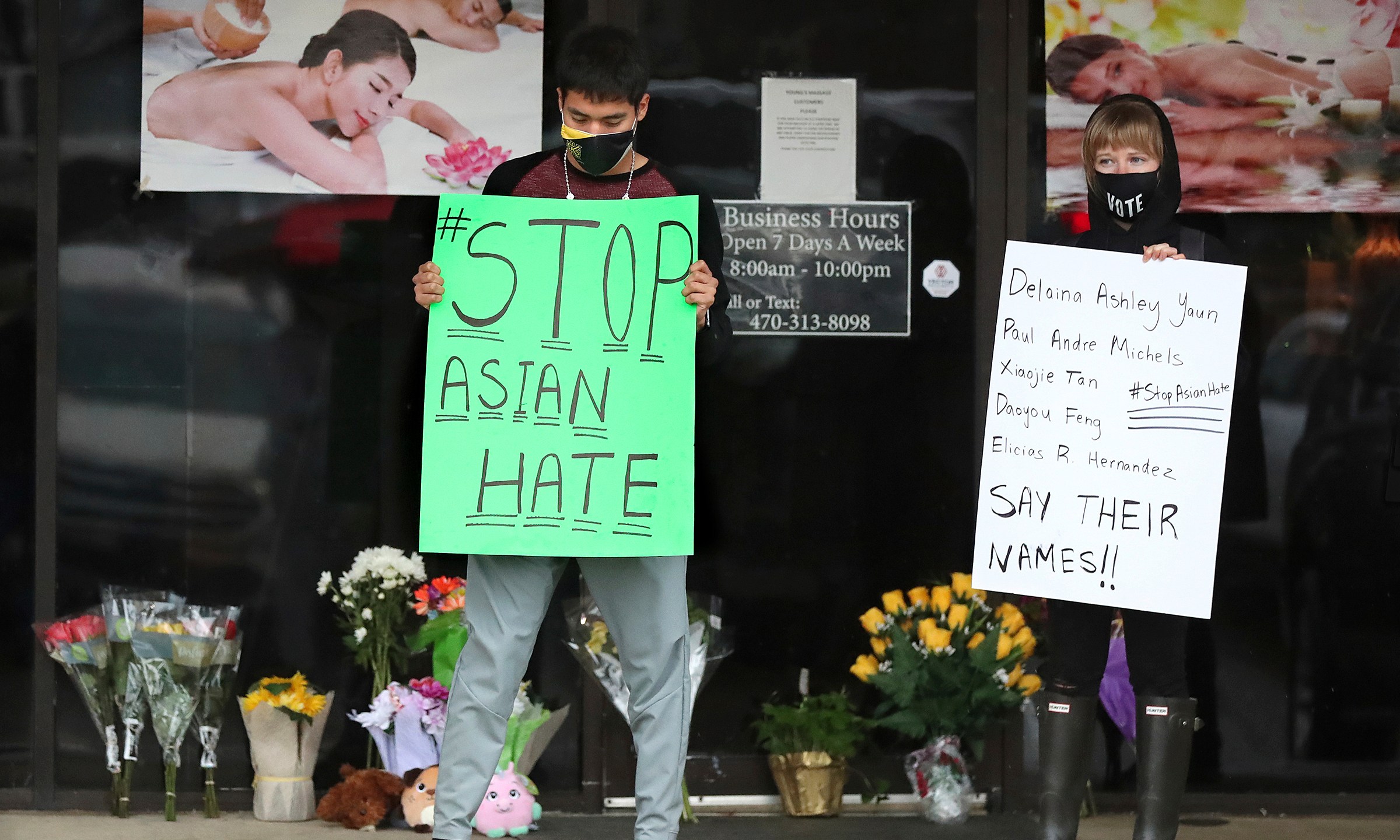 In this March 17, 2021, file photo, after dropping off flowers Jesus Estrella, left, and Shelby stand in support of the Asian and Hispanic community outside Young's Asian Massage in Acworth, Ga. (Curtis Compton /Atlanta Journal-Constitution via AP, File)