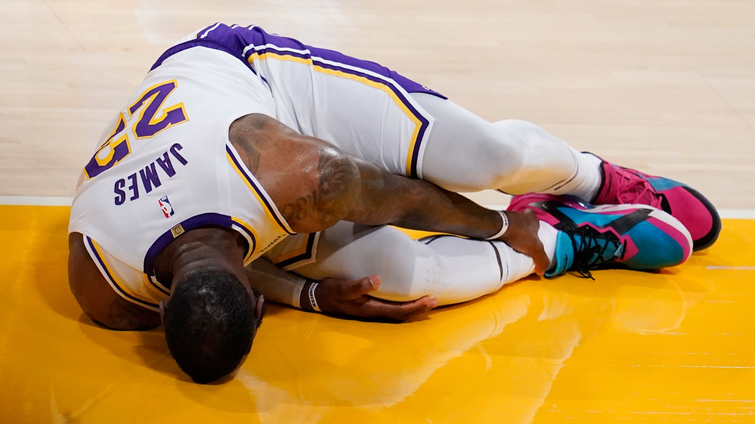 Los Angeles Lakers forward LeBron James holds his ankle after going down with an injury during the first half of an NBA basketball game against the Atlanta Hawks on March 20, 2021, in Los Angeles. (AP Photo/Marcio Jose Sanchez)