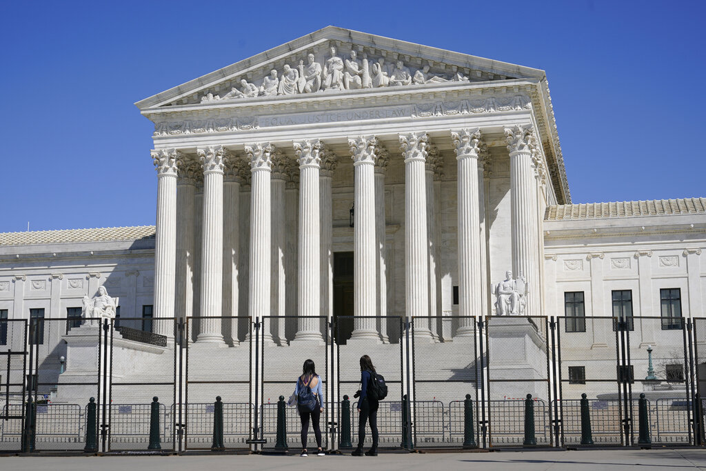 People view the Supreme Court building from behind security fencing on Capitol Hill in Washington, Sunday, March 21, 2021, after portions of an outer perimeter of fencing were removed overnight to allow public access. (AP Photo/Patrick Semansky)