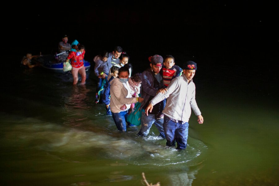 Migrant families, mostly from Central American countries, wade through shallow waters after being delivered by smugglers on small inflatable rafts on U.S. soil in Roma, Texas, Wednesday, March 24, 2021. (AP Photo/Dario Lopez-Mills)