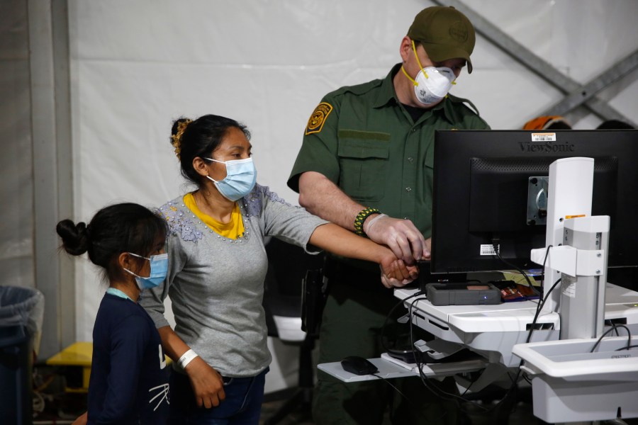 A migrant and her daughter have their biometric data entered at the intake area of the Donna Department of Homeland Security holding facility, the main detention center for unaccompanied children in the Rio Grande Valley, in Donna, Texas, on March 30, 2021. (AP Photo/Dario Lopez-Mills, Pool)