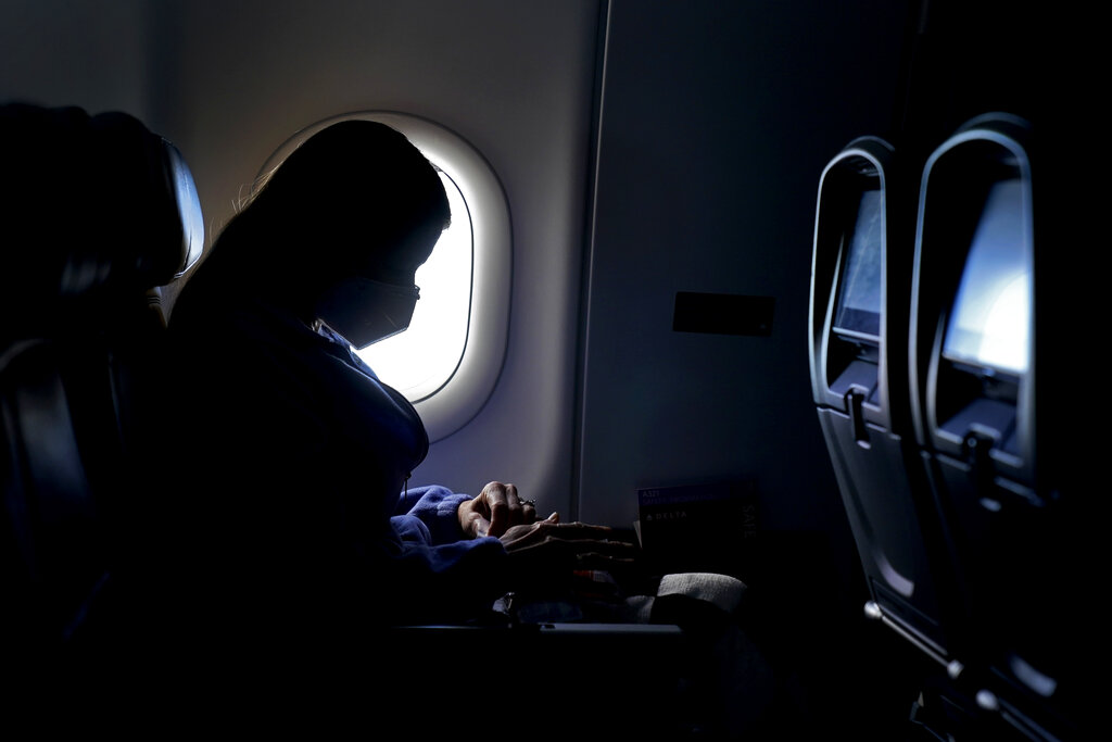 In this Wednesday, Feb. 3, 2021, file photo, a passenger wears a face mask she travels on a Delta Air Lines flight after taking off from Hartsfield-Jackson International Airport in Atlanta. (AP Photo/Charlie Riedel, File)