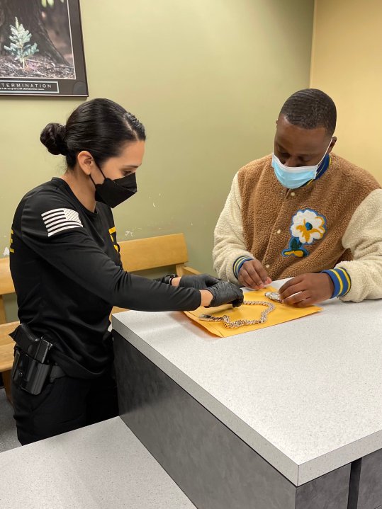 An officer returns jewelry to a victim of a brazen armed robbery. (LAPD)