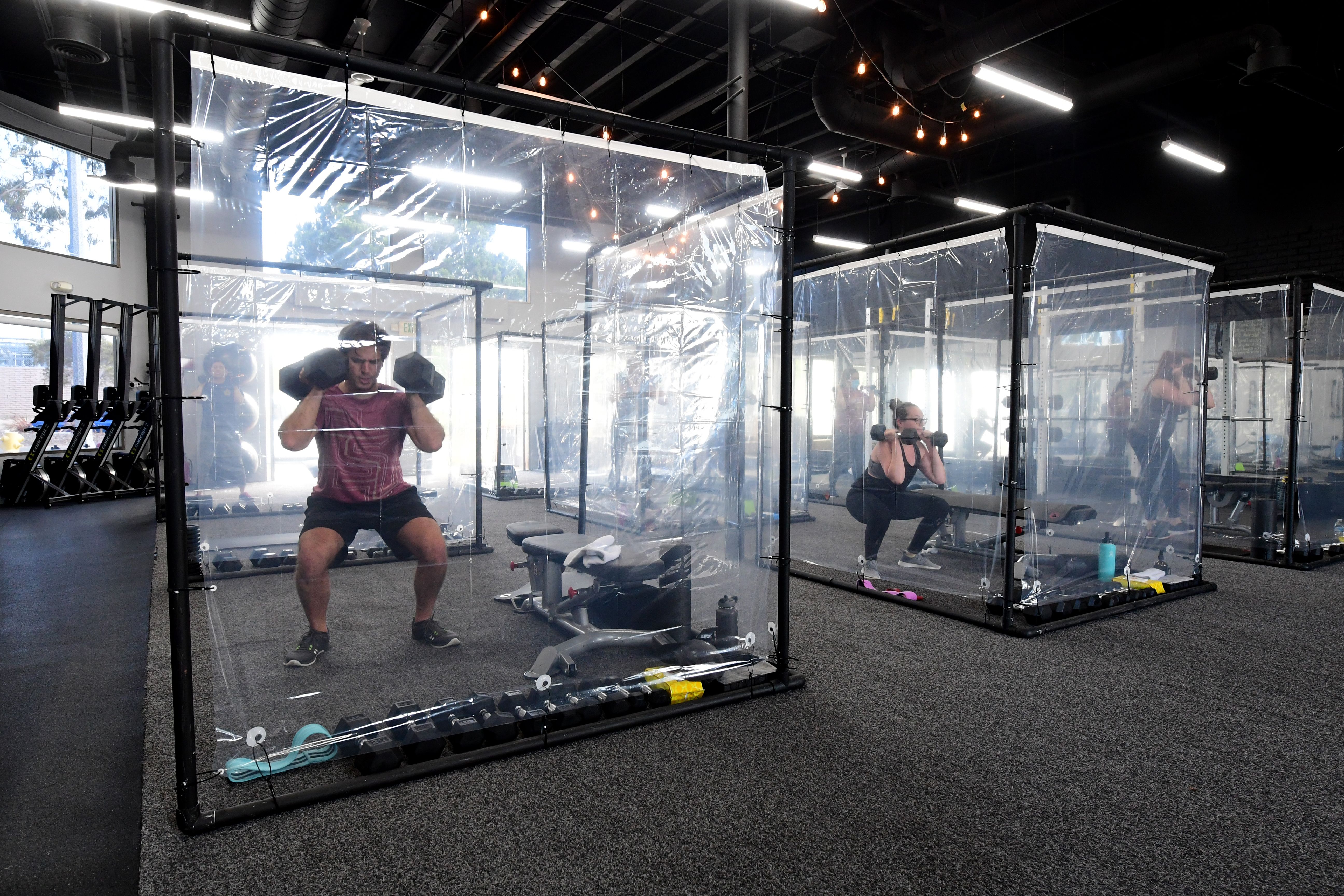 People exercise at Inspire South Bay Fitness behind plastic sheets in their workout pods on June 15, 2020, in Redondo Beach, California. (FREDERIC J. BROWN/AFP via Getty Images)