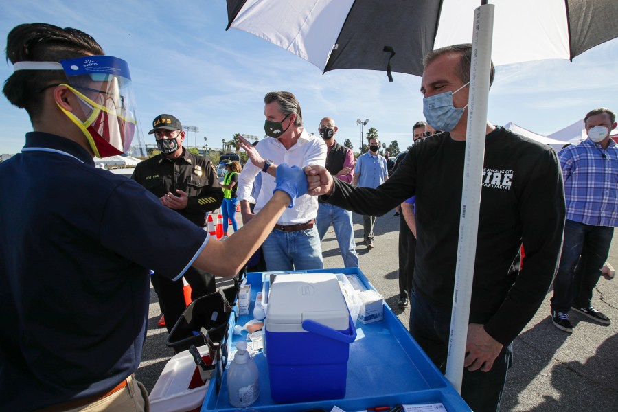 Los Angeles Mayor Eric Garcetti, at right, and California Governor Gavin Newsom, center, tour the mass COVID-19 vaccination site at Dodger Stadium on Jan. 15, 2021. (Irfan Khan / AFP / Getty Images)