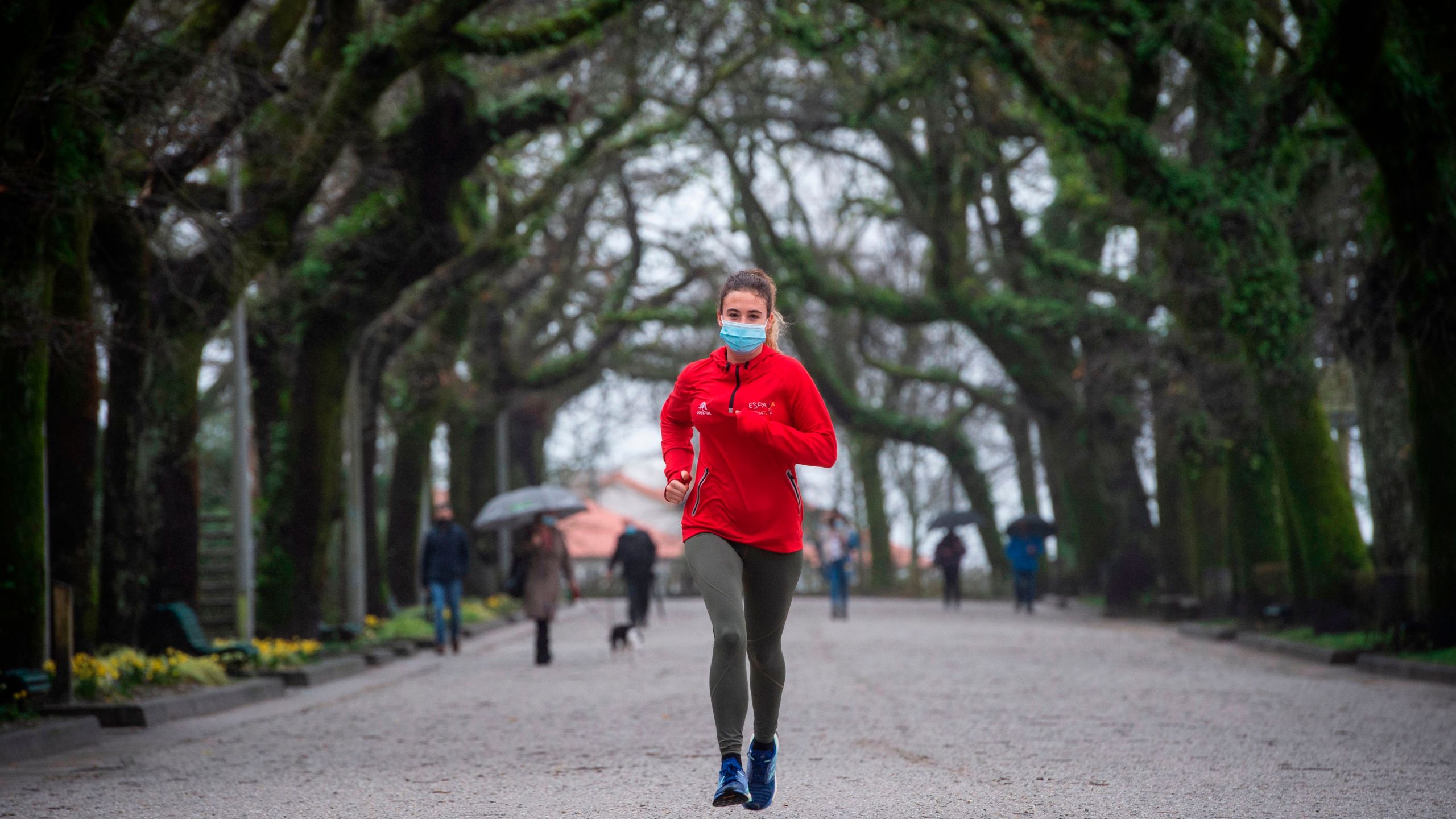 A woman wearing a face mask jogs through a park following new coronavirus restrictions in Santiago de Compostela in northwestern Spain on January 27, 2021. (MIGUEL RIOPA/AFP via Getty Images)