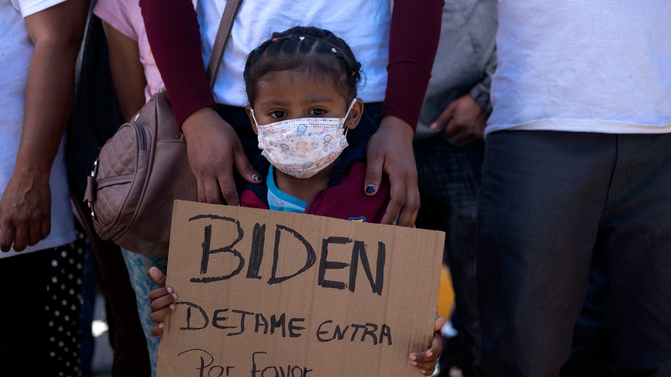 A girl from Honduras holds a sign asking President Joe Biden to let her in during a migrant demonstration demanding clearer U.S. migration policies at the San Ysidro crossing port in Tijuana, Mexico on March 2, 2021. (Guillermo Arias / AFP / Getty Images)