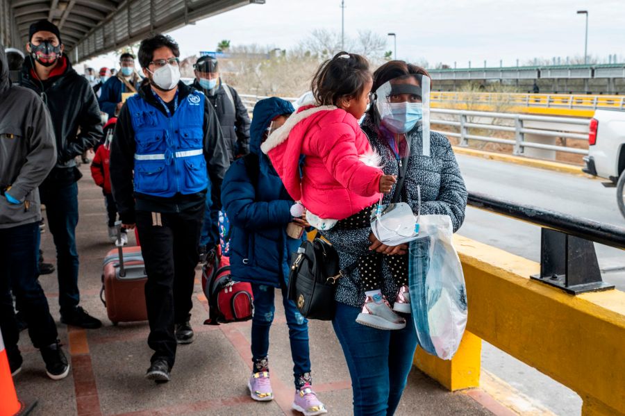 A migrant family approaches the US border on Gateway International Bridge in Brownsville, Texas on March 2, 2021. (SERGIO FLORES/AFP via Getty Images)