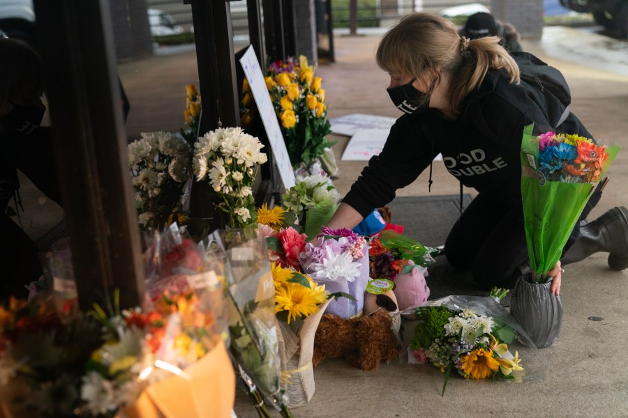 Shelby Swan adjusts flowers and signs outside Youngs Asian Massage where four people were shot and killed on March 17, 2021 in Acworth, Georgia. (Elijah Nouvelage/Getty Images)