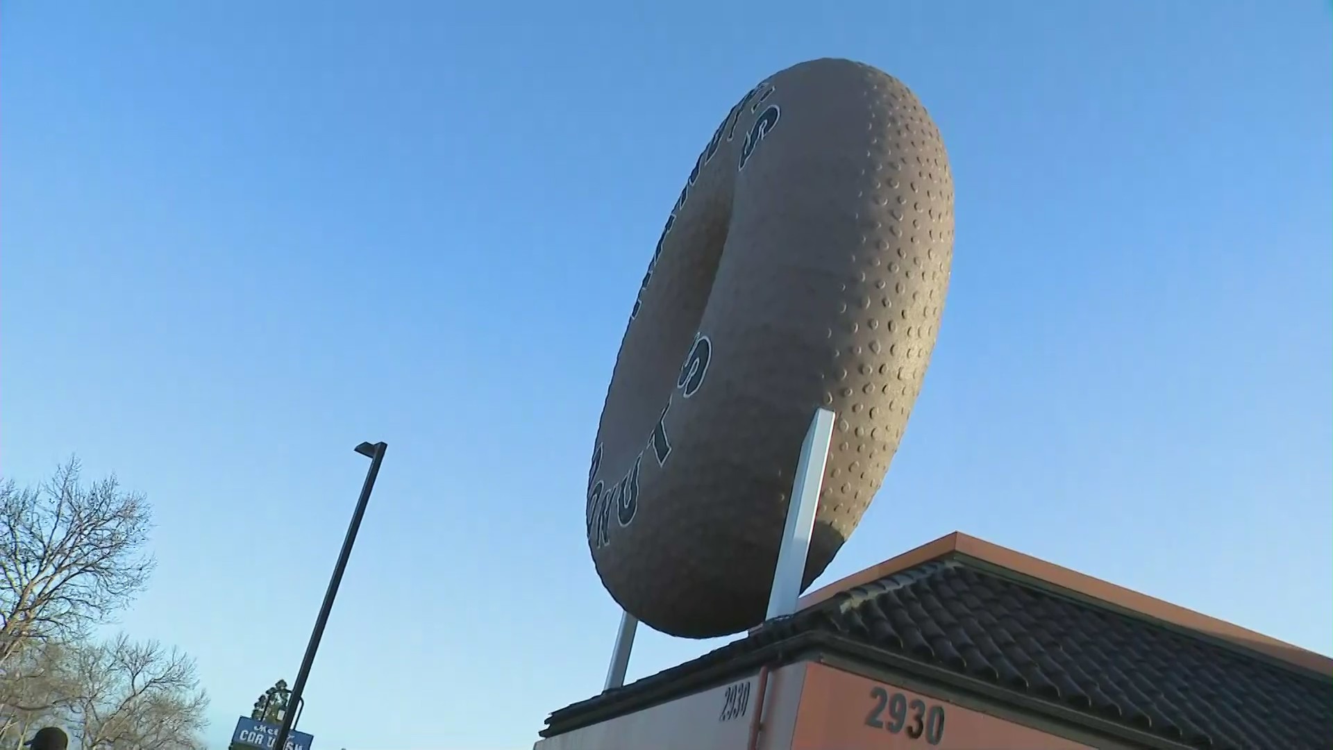 A giant donut on top of Randy's Donuts is seen during the shop's grand opening in Costa Mesa on March 9, 2021. (KTLA)