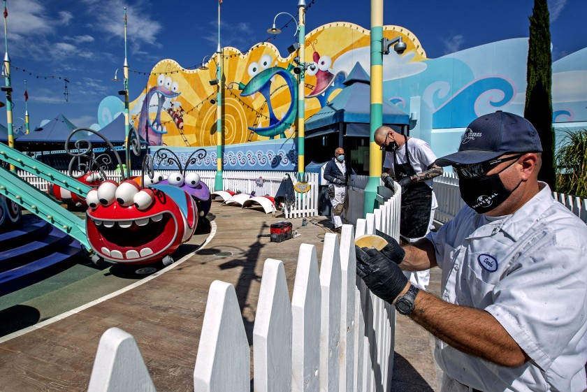 Scenic artists Billy Teichert, Jason Young and Carlos Rivas prepare to paint a fence next to a ride at Universal Studios Hollywood in this undated photo. The park, closed for more than a year, plans to open in late April. (Mel Melcon / Los Angeles Times)