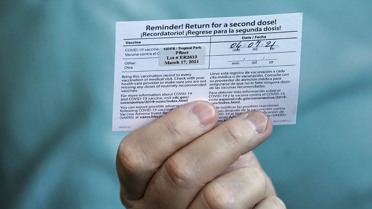 Juan Carlos Guerrero, 62 holds his second shot reminder card as he speaks to a healthcare worker after having received a dose of the Pfizer's COVID-19 vaccine on March 17, 2021, at the Miami-Dade County Tropical Park vaccination site in Miami. (AP Photo/Wilfredo Lee)