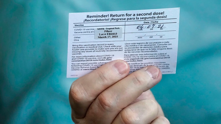 Juan Carlos Guerrero, 62 holds his second shot reminder card as he speaks to a healthcare worker after having received a dose of the Pfizer's COVID-19 vaccine on March 17, 2021, at the Miami-Dade County Tropical Park vaccination site in Miami. (AP Photo/Wilfredo Lee)