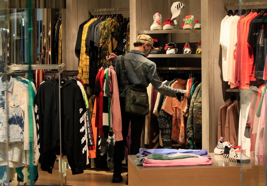 A manager at a boutique sets up new clothes for the store opening of Beverly Center shopping mall in Los Angeles on May 29, 2020. (AP Photo/Damian Dovarganes)