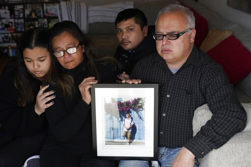 Cassandra Quinto-Collins, second from left, holds a photo of her son, Angelo Quinto, while sitting with daughter Bella Collins, left, son Andrei Quinto, center, and husband Robert Collins during an interview in Antioch, Calif., March 16, 2021. (AP Photo/Jeff Chiu)