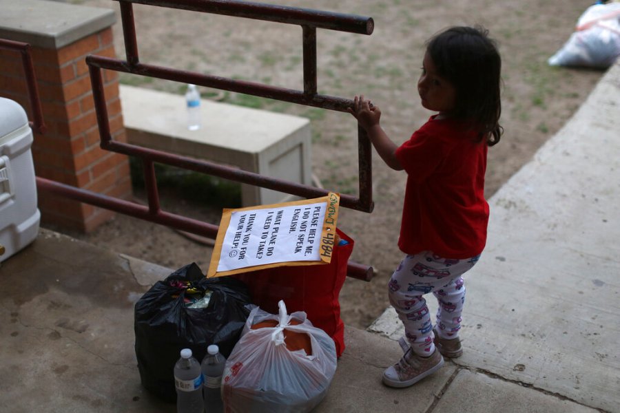 A chid stands next to her family's belongings as they wait for transportation at Our Lady of Guadalupe Catholic Church in McAllen, Texas, on Palm Sunday, March 28, 2021. (AP Photo/Dario Lopez-Mills)