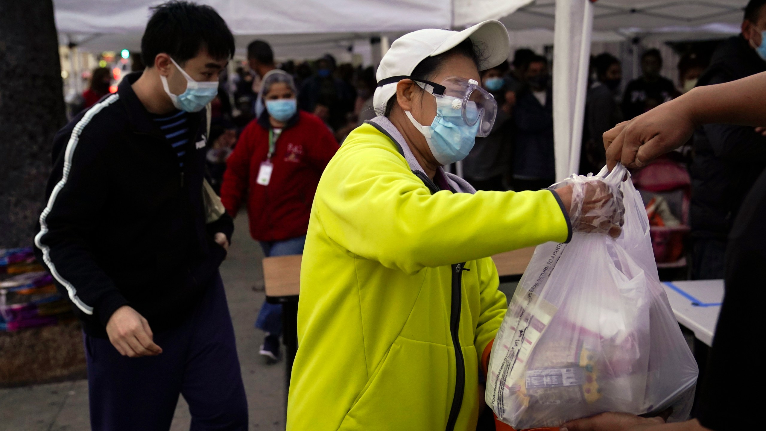 In this Dec. 17, 2020, file photo, a woman receives a bag of groceries at a food bank at the Los Angeles Boys & Girls Club in the Lincoln Heights neighborhood of Los Angeles. (AP Photo/Jae C. Hong, File)