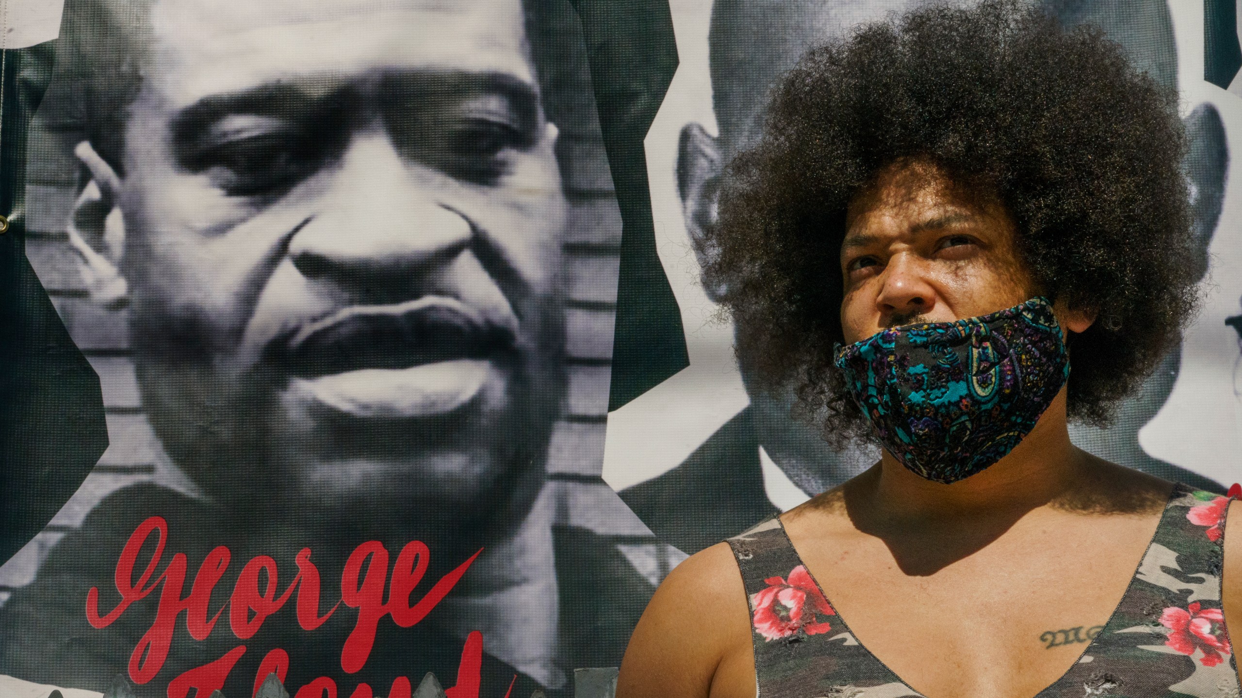 Actor Steven Thompson poses for a picture next to a poster of George Floyd in Los Angeles Friday, April 2, 2021. Thompson is choosing not to watch the televised trial of Derek Chauvin, the white police officer charged in the death of George Floyd, has provoked strong emotions among many Black men and women, all tinged with an underlying dread that it could yield yet another devastating disappointment, even though he feels there is a strong case against him. (AP Photo/Damian Dovarganes)