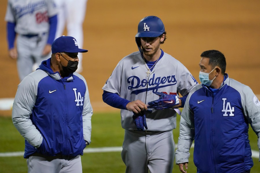 Los Angeles Dodgers' Cody Bellinger, center, walks off the field as he leaves the game with manager Dave Roberts, left, and a trainer during the ninth inning of a baseball game against the Oakland Athletics in Oakland on April 5, 2021. (Jeff Chiu / Associated Press)