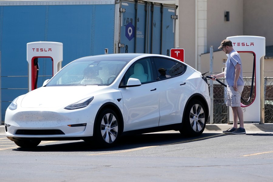 A Tesla owner charges his vehicle at a charging station in Topeka, Kan., Monday, April 5, 2021. (AP Photo/Orlin Wagner)