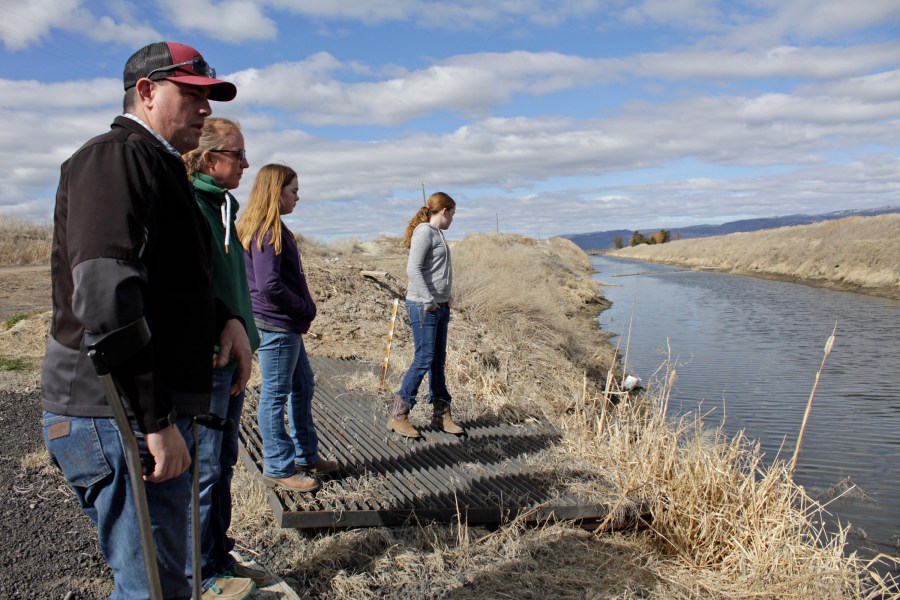 In this March 2, 2020, file photo, farmer Ben DuVal with his wife, Erika, and their daughters, Hannah, third from left, and Helena, fourth from left, stand near a canal for collecting run-off water near their property in Tulelake, Calif. (AP Photo/Gillian Flaccus, File)