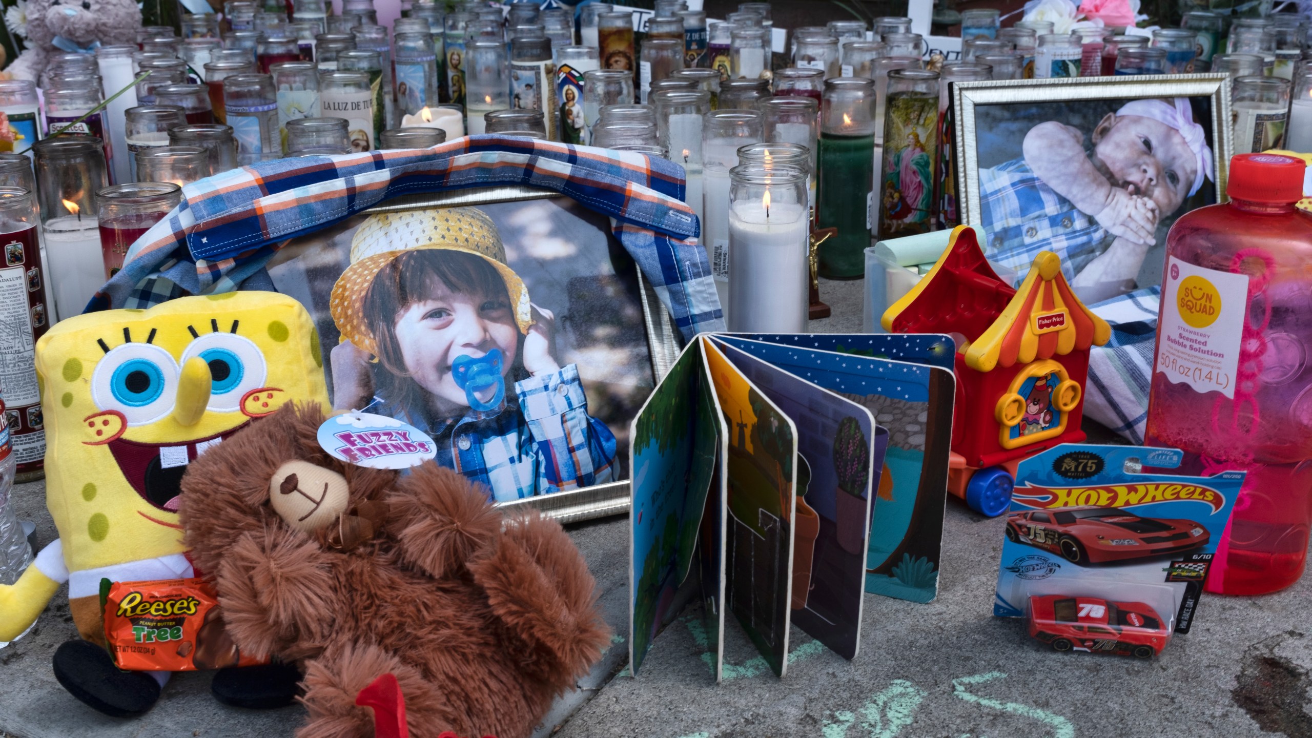 Photos, candles, flowers and balloons are placed as a memorial on April 12, 2021, for three children who were killed at the Royal Villa apartments complex in Reseda. (Richard Vogel / Associated Press)