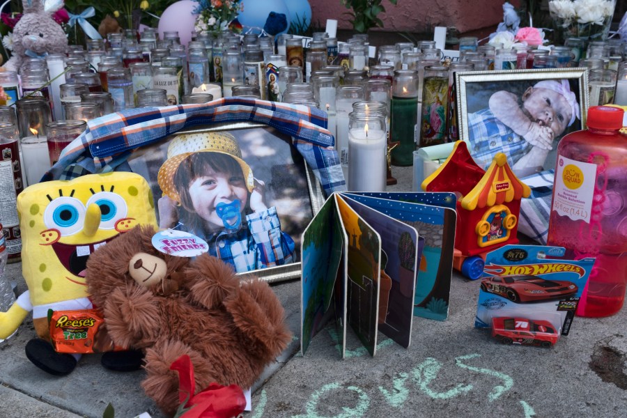 Photos, candles, flowers and balloons are placed as a memorial on April 12, 2021, for three children who were killed at the Royal Villa apartments complex in Reseda. (Richard Vogel / Associated Press)