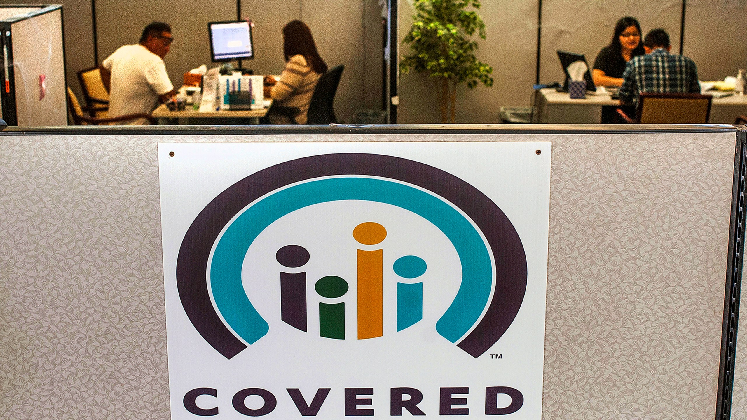 In this Nov. 1, 2016, file photo, agents help sign people up for insurance through the Covered California exchange at their storefront in Huntington Beach, Calif. (Nick Agro/The Orange County Register via AP, File)