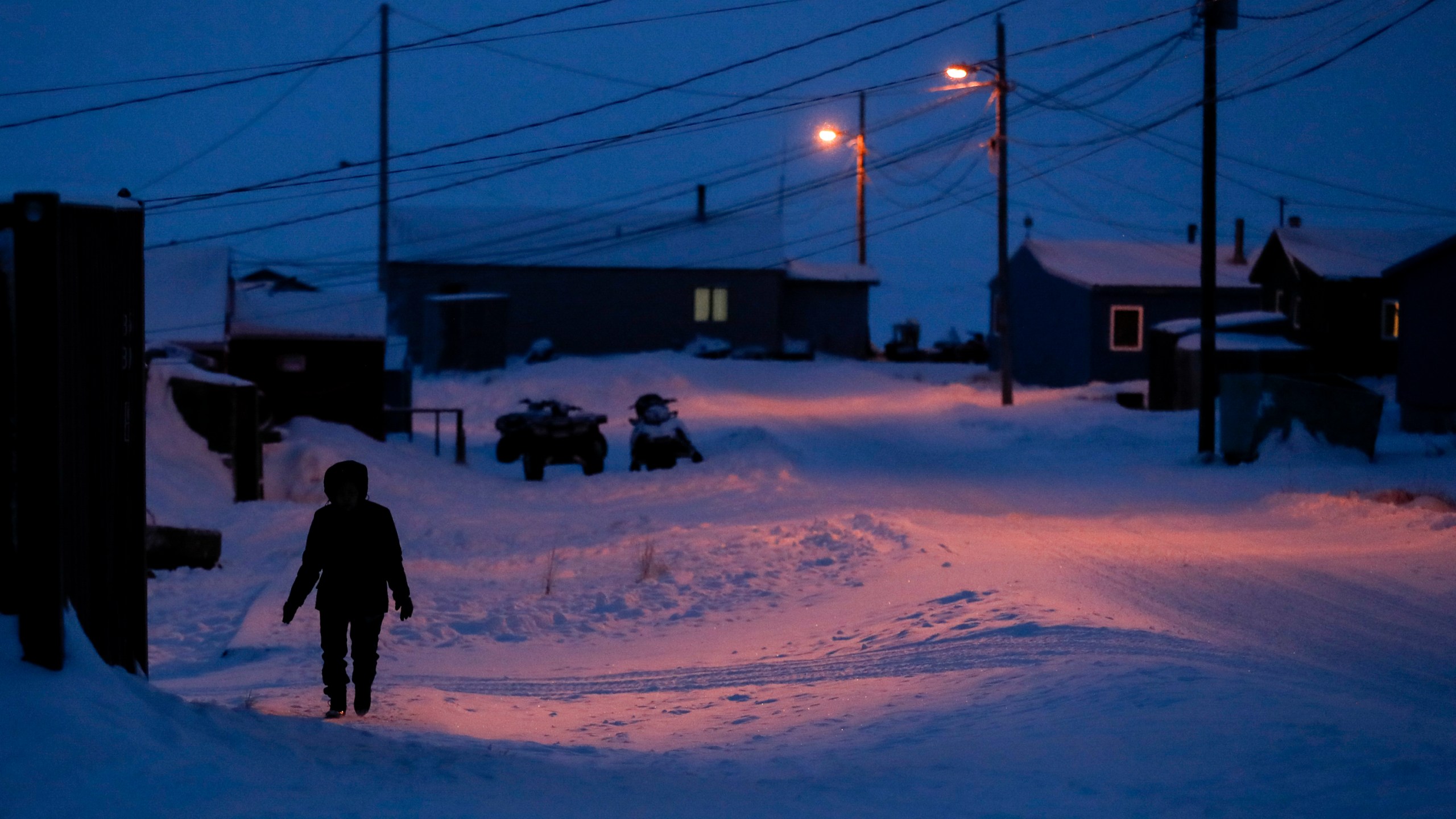 FILE - In this Jan. 20, 2020, file photo, a woman walks before dawn in Toksook Bay, Alaska, a mostly Yuip'ik village on the edge of the Bering Sea. The U.S. Supreme Court will hear oral arguments Monday, April 19, 2021, in a case that will determine who is eligible to receive more than $530 million in federal virus relief funding set aside for tribes more than a year ago. More than a dozen Native American tribes sued the U.S. Treasury Department to keep the money out of the hands of Alaska Native corporations, which provide services to Alaska Natives but do not have a government-to-government relationship with the United States. (AP Photo/Gregory Bull, File)