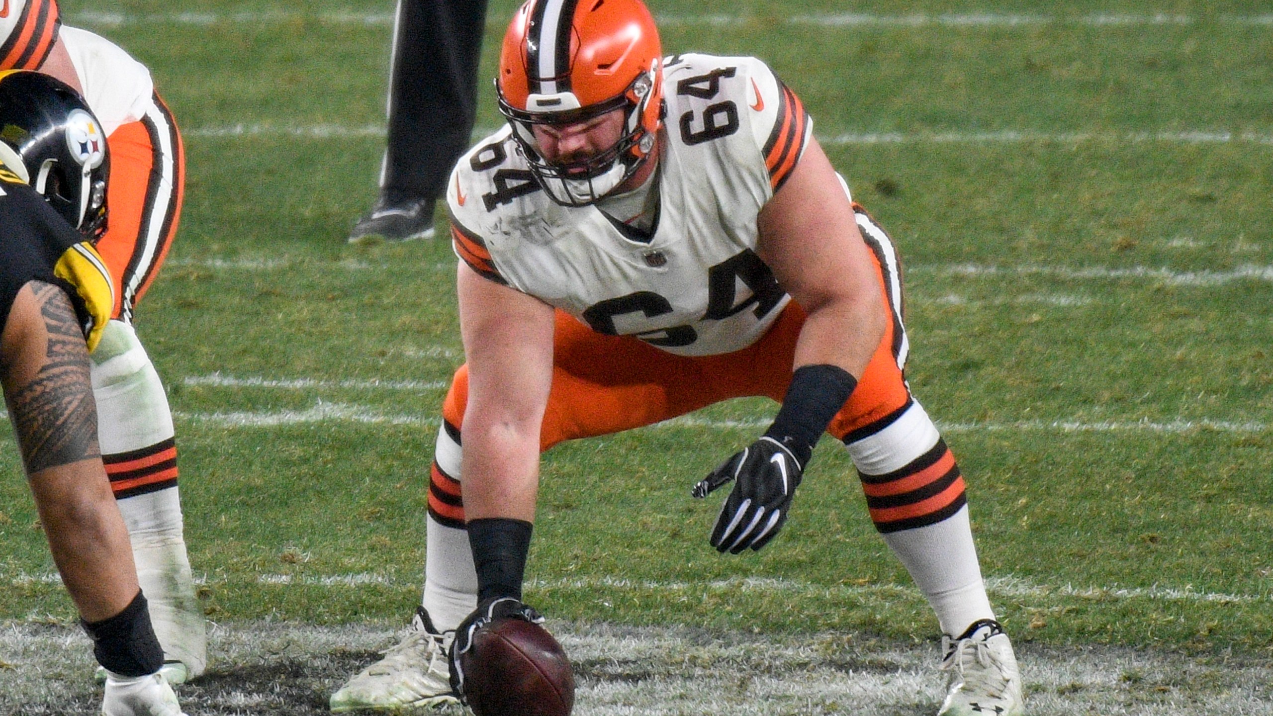 FILE - In this Jan. 10, 2021, file photo, Cleveland Browns center JC Tretter (64) snaps the ball during the first half of an NFL wild-card playoff football game against the Pittsburgh Steelers in Pittsburgh. Following the advice of Browns center and NFL Players Association President Tretter, Cleveland's players joined a list of teams who say they will skip voluntary in-person workouts this offseason. (AP Photo/Don Wright, File)