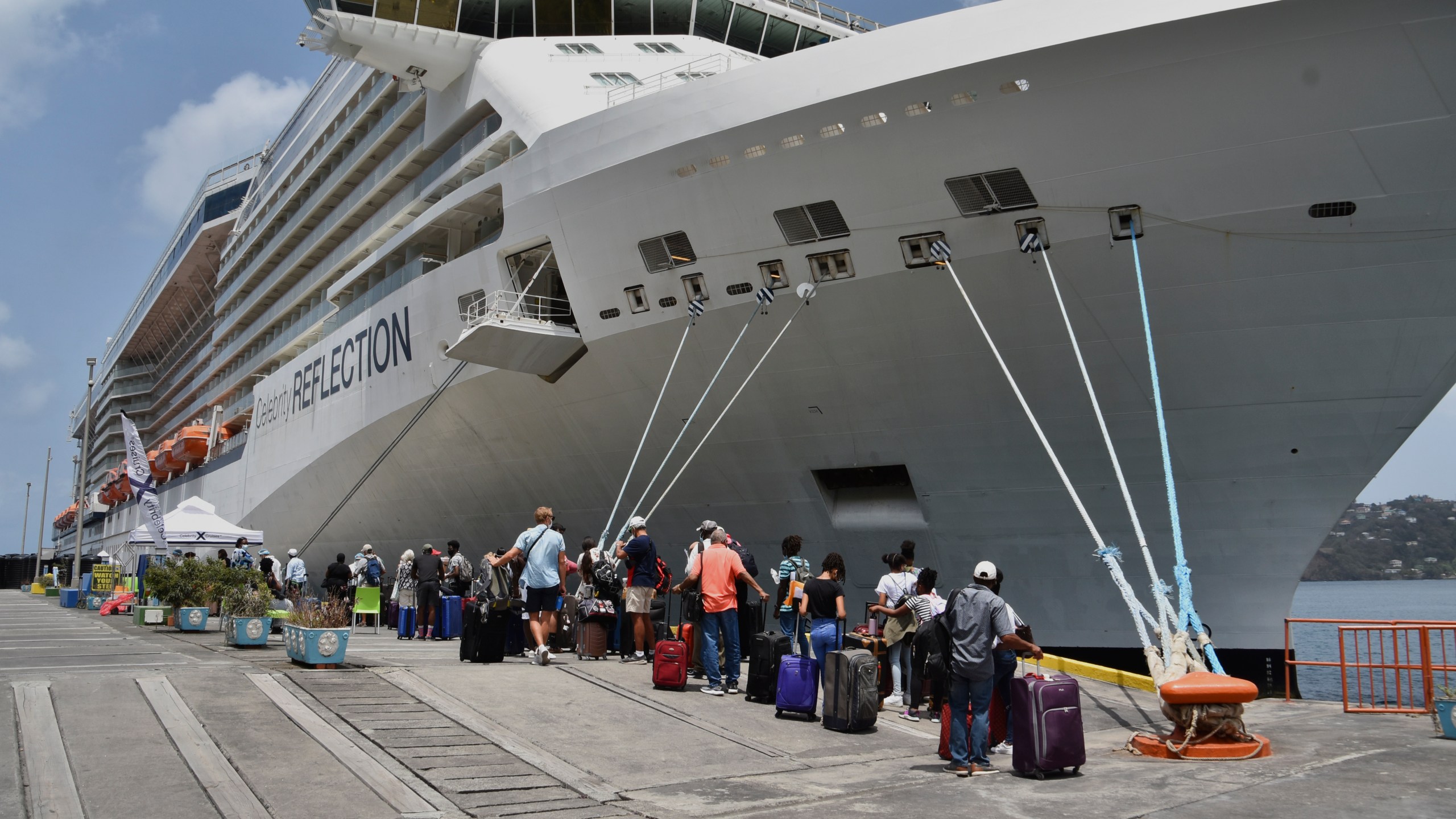 British, Canadian and U.S. nationals line up alongside the Royal Caribbean cruise ship Reflection to be evacuated free of charge, in Kingstown on the eastern Caribbean island of St. Vincent, Friday, April 16, 2021. La Soufriere volcano has shot out another explosive burst of gas and ash Friday morning as the cruise ship arrived to evacuate some of the foreigners who had been stuck on a St. Vincent island by a week of violent eruptions. (AP Photo/Orvil Samuel)