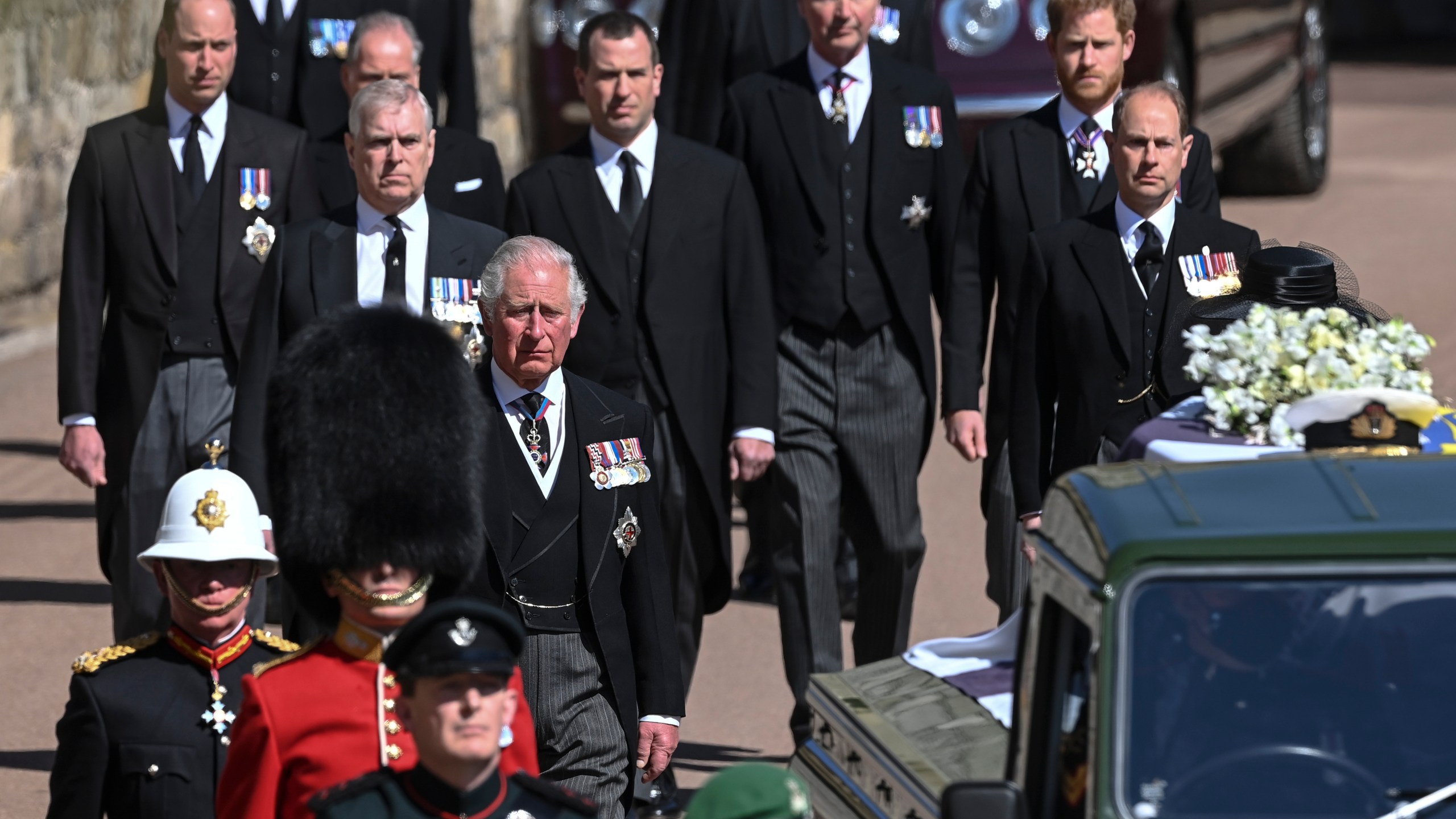 From front left, Britain's Prince Charles, Prince Andrew. Prince Edward, Prince William, Peter Phillips, Prince Harry, Earl of Snowdon and Tim Laurence follow the coffin the coffin makes it's way past the Round Tower during the funeral of Britain's Prince Philip inside Windsor Castle in Windsor, England Saturday April 17, 2021. (Leon Neal/Pool via AP)