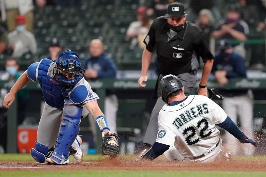 Seattle Mariners' Luis Torrens slides safely home as Los Angeles Dodgers catcher Will Smith attempts the tag during the fourth inning of a baseball game in Seattle on April 19, 2021. (Ted S. Warren / Associated Press)