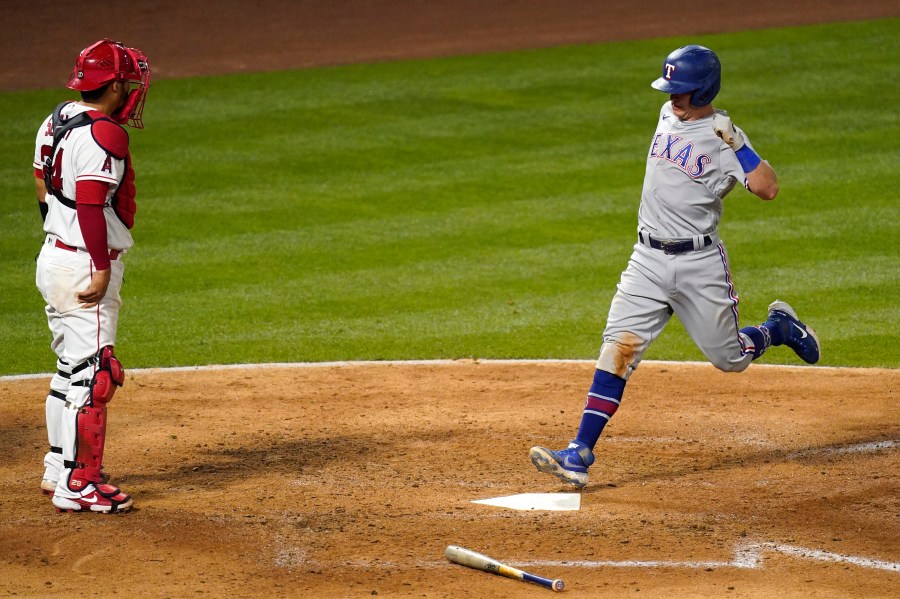 Texas Rangers' Nick Solak, right, scores on a sacrifice fly hit by Jose Trevino as Los Angeles Angels catcher Kurt Suzuki stands at the plate during the sixth inning of a baseball game in Anaheim on April 19, 2021. (Mark J. Terrill / Associated Press)