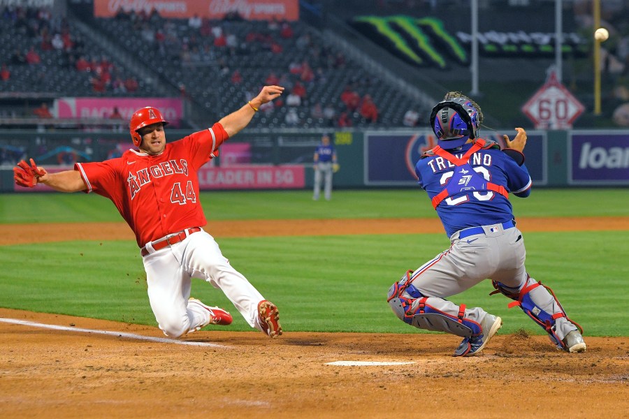 Los Angeles Angels' Scott Schebler, left, scores on a sacrifice fly hit by David Fletcher as Texas Rangers catcher Jose Trevino takes a late throw during the third inning of a baseball game in Anaheim on April 20, 2021. (Mark J. Terrill / Associated Press)