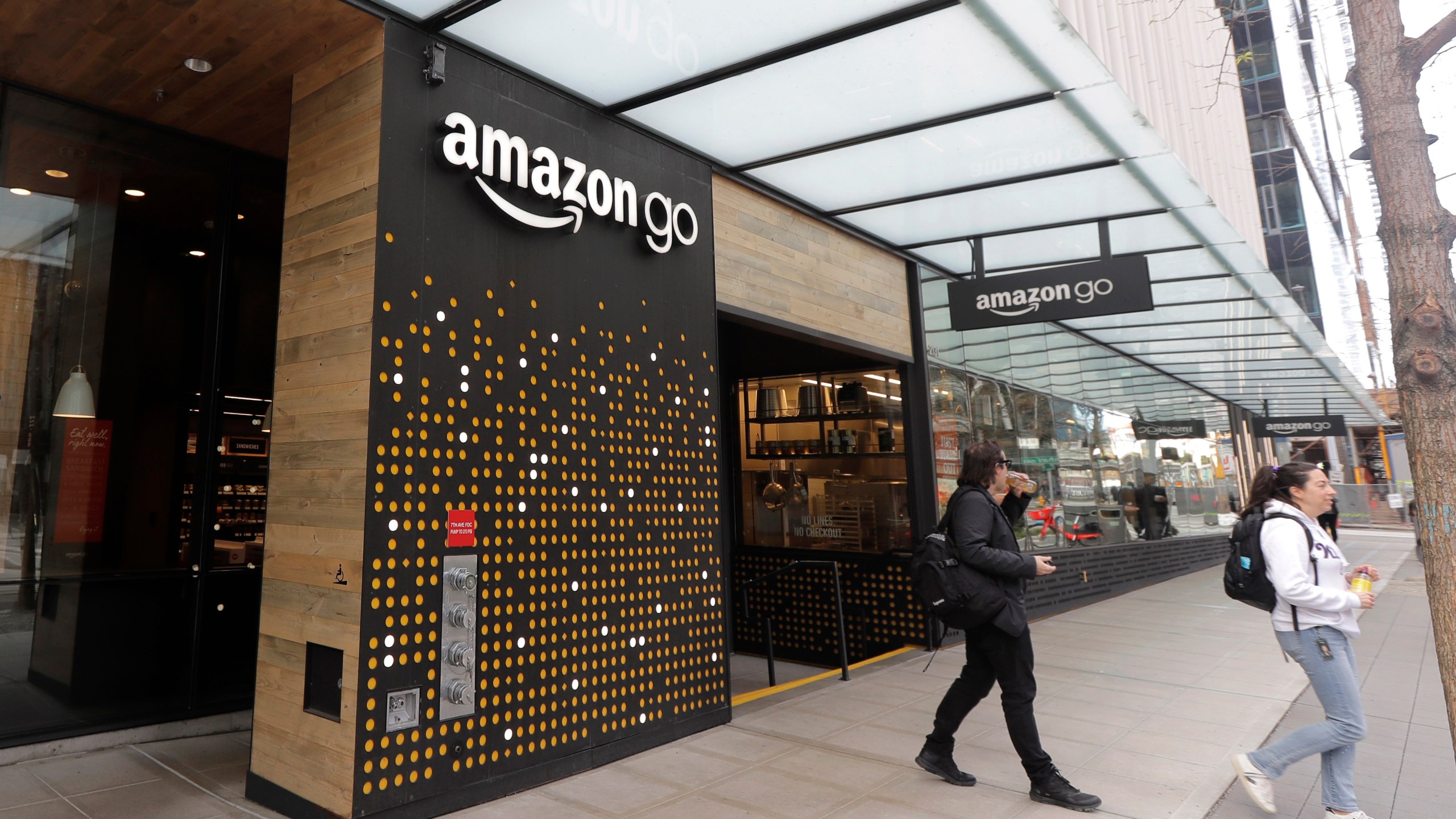 In this March 4, 2020 file photo, people walk out of an Amazon Go store, in Seattle. Amazon said Wednesday, April 21, 2021 that it is rolling out its pay-by-palm technology to some of its Whole Foods supermarkets. The technology, called Amazon One, lets shoppers scan the palm of their hand and connect it to their credit card or Amazon accounts. (AP Photo/Ted S. Warren, File)